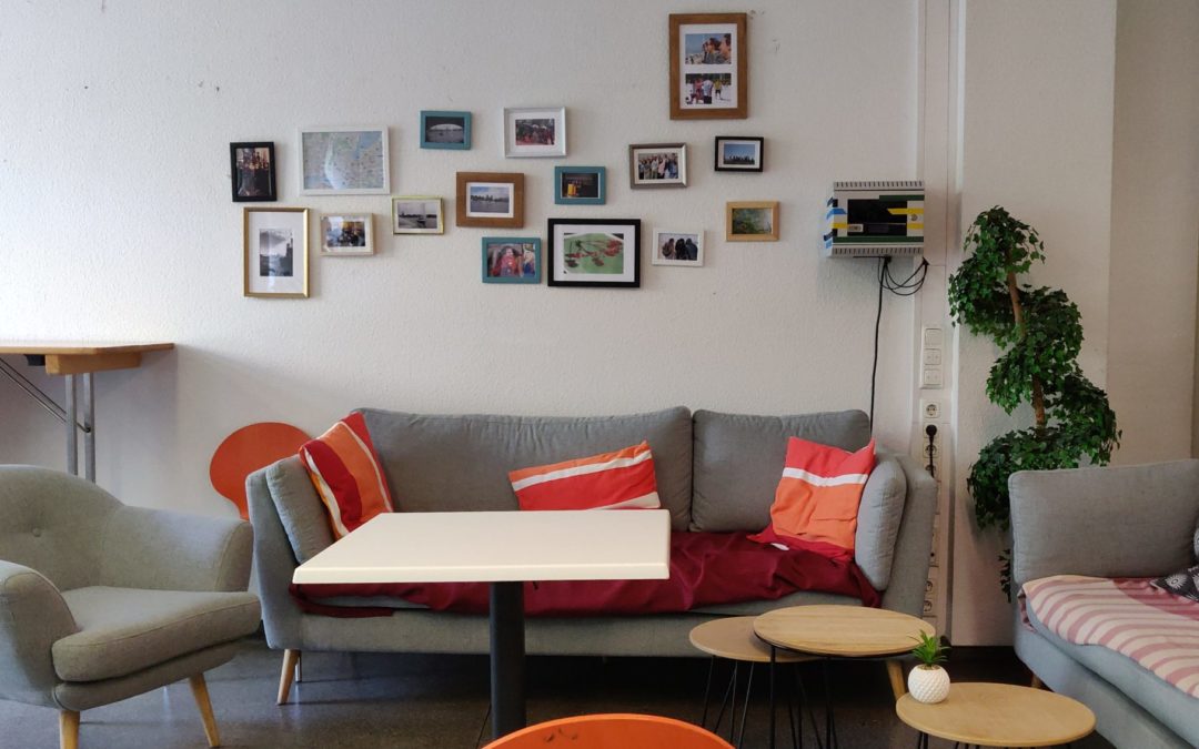 A photo from the language café rooms. There are some couches, tables, and pictures on the wall